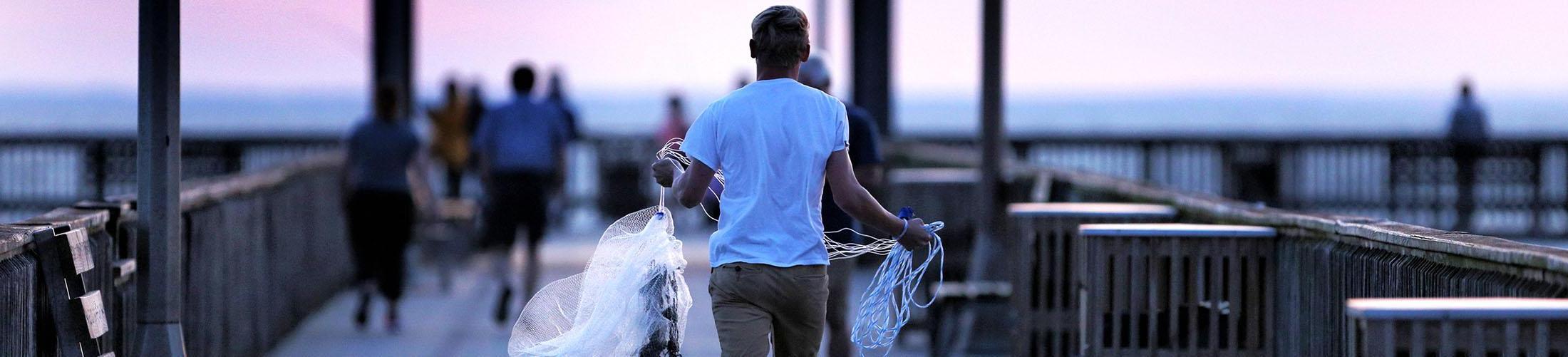 在墨西哥湾沿岸的公平希望码头，一名男子正在搬运渔网.